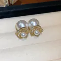 Close-up view of gold flower earrings with white pearls in a jewelry tray - Flower Shape / Gold