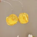 Exquisite Detailaufnahme von gelben Chiffon-Blumenohrringen mit eleganten Metallhaken - Haken-Stil / Gelb