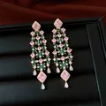 Gros plan de luxueuses boucles d'oreilles fleurs plaquées or 18k avec des zircons roses. - Style Fleur Pompon (HE34195) / Base Dorée avec Zirconia Rose et Vert