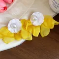 Detailed view of yellow chiffon petals and white pearl flower earrings on a wooden background - Yellow