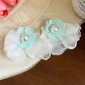 Macro view showing delicate mint green chiffon flower and pearl detail on white earrings - White
