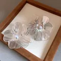 Macro view of silver-toned brushed metal flower earrings with central pearl detail - Brushed Flower Style (HE33829) / Clip-On Earrings / Silver