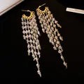 Gros plan d'élégantes boucles d'oreilles à pompons dorés et perles de cristal - Or