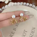 Eleganti orecchini a fiocco placcati oro con perle delicate e cristalli luccicanti - Orecchini di Perle con Fiocco / Oro