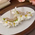 Close-up of elegant white fabric flower hairpins displayed on a vintage wooden tray - White