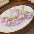 Close-up view of elegant purple fabric flower hairpins with golden metal U-shaped forks. - Purple
