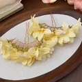 Detailed view of pale yellow fabric flower hairpins with golden U-shaped pins - Yellow