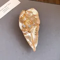 Primo piano di spilla a foglia d'oro artistica con dettaglio orecchio e strass - Oro