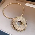 Close-up of gold-colored sunburst pendant necklace with rhinestones and bee detail - Necklace / Gold