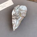 Primo piano di una spilla a forma di orecchio in argento con strass e cerchi dorati. - Argento
