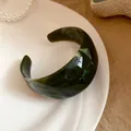 Dettaglio del bracciale rigido geometrico in acrilico marmorizzato verde scuro su piatto - verde scuro