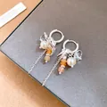 Primer plano de pendientes de golondrina de plata con perlas y borlas de cristal sobre gris - Clip de Oreja de Golondrina con Borla / Plata-Café