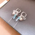 Detalle de pendientes de aro plateados con golondrinas, perlas y cristales azules - Clip de Oreja de Golondrina con Borla / Plata-Azul