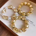 Detailed macro view of gold foil textured geometric beads and elegant white pearls - Three-Piece Set / Gold
