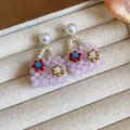 Close-up of pink beaded handbag earrings with floral accents and white pearls - Pink