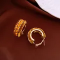 Dettaglio di eleganti orecchini a cerchio dorati con cristalli ambrati scintillanti - Marrone oro