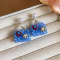 Detail view of blue beaded handbag earrings with pearl studs on jewelry box - Blue