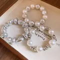 Close-up of retro irregular silver and pearl beaded bracelets on a vintage tray. - Three-Piece Set / Silver