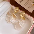 Macro detail view of 14k gold plated tassel earrings with layered white shell rounds - Tassel Style (HE33805) / Gold-White