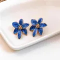 Dettaglio di orecchini a lobo a forma di fiore in smalto blu con bordi dorati - Blu