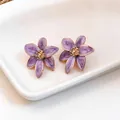 Vista dettagliata degli orecchini a lobo a fiore in smalto viola con accenti dorati - Viola