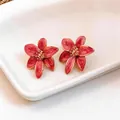 Dettaglio di orecchini a lobo a fiore in smalto rosa con stami dorati - Rosa Rosso