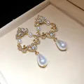 Detail view of gold filigree earrings with teardrop pearls and crystals - Single Pair of Earrings / Gold-White