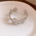 Detailansicht eines eleganten silbernen Blumen-Armreifs auf einem Keramikteller. - Silber