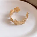 Nahaufnahme der filigranen goldfarbenen Blütenblätter und der matten Textur dieses Armreifs - Gold