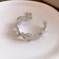 Detailansicht eines silbernen Metall-Armreifs im Vintage-Stil mit verbundenen Blumen. - Silber