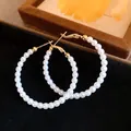 Elegant vintage gold-toned hoop earrings with white pearl beads on black velvet surface - Silver Earring Post-White