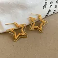 Detailed macro shot of 18k gold plated star stud earrings with textured surface design - Gold