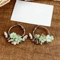 Detailed view of silver hoop earrings with delicate green resin flowers and beads. - Green