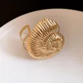 Vue rapprochée d'un bracelet jonc ouvert en forme de coquillage doré avec finition texturée. - Or