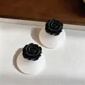 Detailed view of elegant black resin rose stud earrings with pearly white disc base design. - Black - Transparent