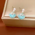 Primo piano di orecchini a conchiglia blu con perle e stella marina su scatola dorata. - Forma di Conchiglia (HE33996) / Blu