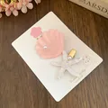 Detailliertes Set aus zwei Harz-Haarspangen mit rosa Muschel und weißem Seestern mit Perlen. - Rosa Weiß