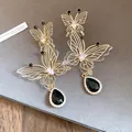 Detailansicht von Schmetterlings-Ohrringen mit schwarzen Kristallen und Gold-Filigran. - Gold Schwarz