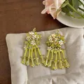 Detailed macro shot of yellow sequin flower earrings featuring glass tassel accents - Silver Earring Post-Green