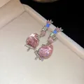 Detail close-up of pink strawberry earrings with sparkling multi-colored stones. - Colorful