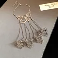Dettaglio macro del bracciale schiava con farfalla traforata d'argento e quattro anelli - Argento