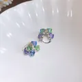 Gros plan de boucles d'oreilles géométriques avec des cristaux cubiques multicolores. - Multicolore (Bleu Vert Violet)
