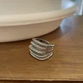 Detailed macro view of a silver-tone multi-layer textured open ring on a wooden surface - Open Ring / Silver
