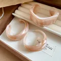 Detail view of irregular peach marbled resin cuff bangles in a display box - Pink