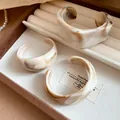 Close-up of irregular geometric resin bangles with brown marble ink pattern - Khaki