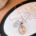 Detailaufnahme eines goldfarbenen Anhängers mit einer braunen Harzperle und Textur. - Kaffeegold