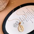 Makroansicht einer goldfarbenen Halskette mit strukturiertem Wellenanhänger und Harzperlen. - Gold