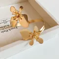 Eleganter goldener Blumen-Armreif mit minimalistischem, gedrehtem Blumendesign. - Gold