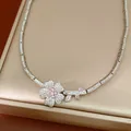 Close-up detail of a silver-toned necklace with a sparkling zircon flower pendant - Necklace / Silver-Pink