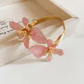 Eleganter goldener Armreif mit rosa marmorierten Emaille-Blüten im Minimal-Stil. - Gold-Rosa